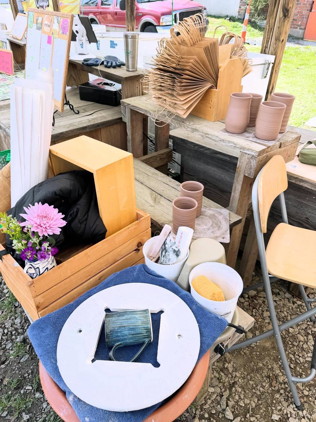 A pottery wheel set up at an outdoor market stall, with a ball of clay ready to throw