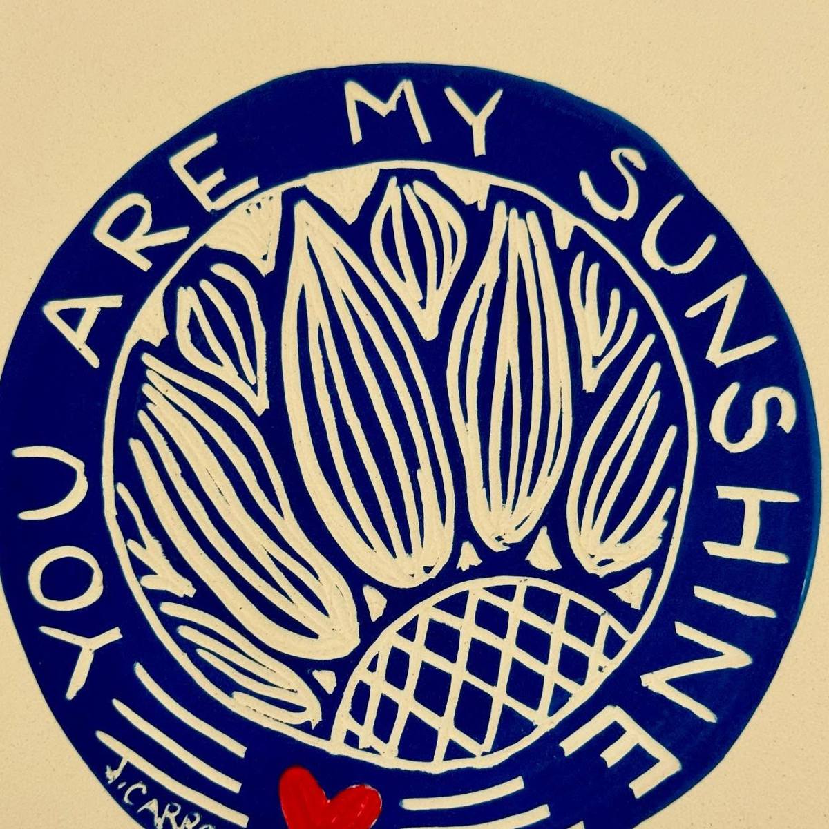 Underside of a platter carved with the words You Are My Sunshine around a sunflower